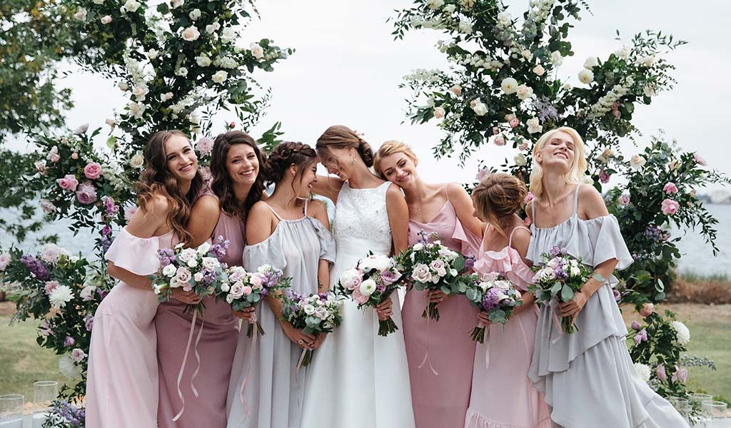 Photo of A bride poses with her bridesmaids in coordinated outfits